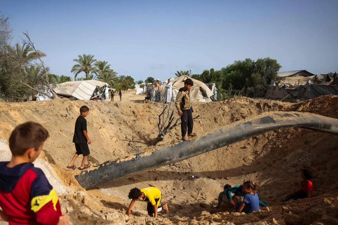 Palestinian children gather around a crater following overnight Israeli bombardment in Khan Younis, in the southern Gaza Strip, on May 19.