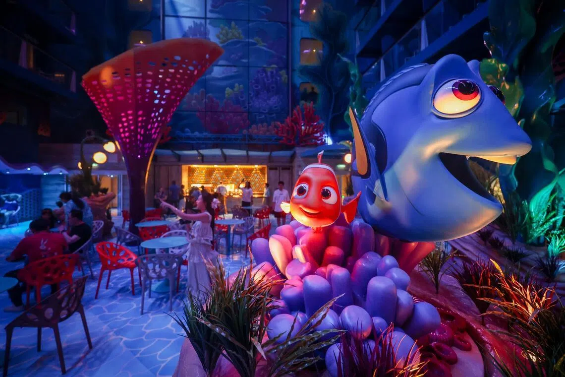 The Disney Discovery Reef is flanked by towering blue walls, coral structures and sand mounds dotted with aquatic plants.