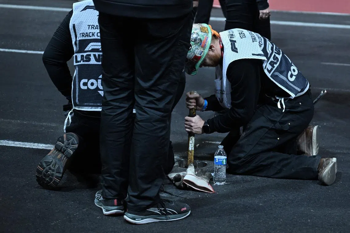 A worker hammering in sand used to fill a drain hole on the track during the first practice session for the Las Vegas Formula One Grand Prix on Nov 16. 