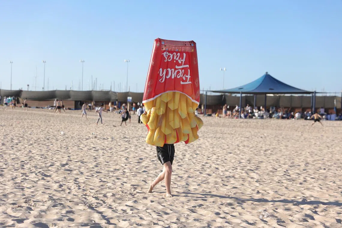 An Ultra Orthodox Jewish man carrying a sea mattress as he enjoys summer time at the beach with families at the separate beach in the southern city of Ashdod, Israel, 02 August 2023. In Israel there are 16 separate bathing beaches for the ultra-orthodox public.