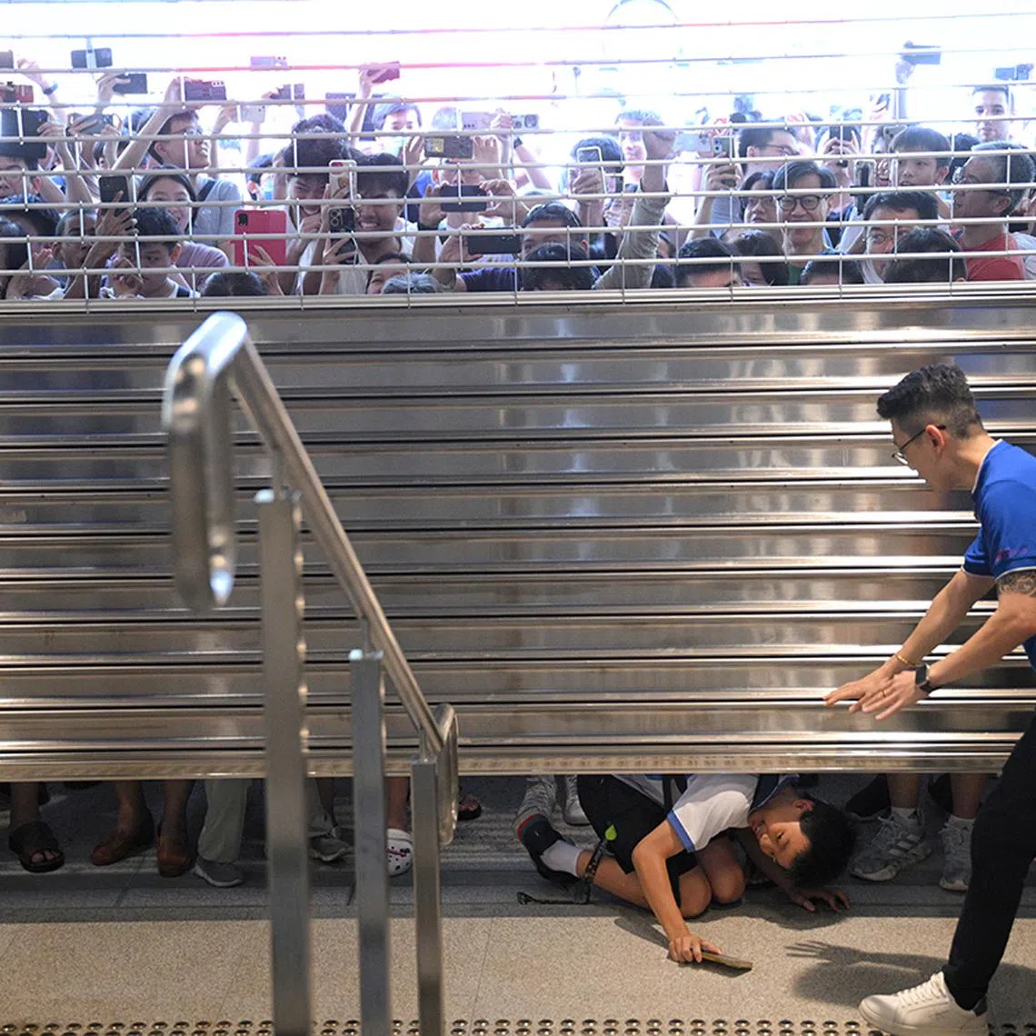 A boy trying to sneak under the shutters as Hume MRT station was opened to the public for the first time at 3pm on Feb 28, 2025.