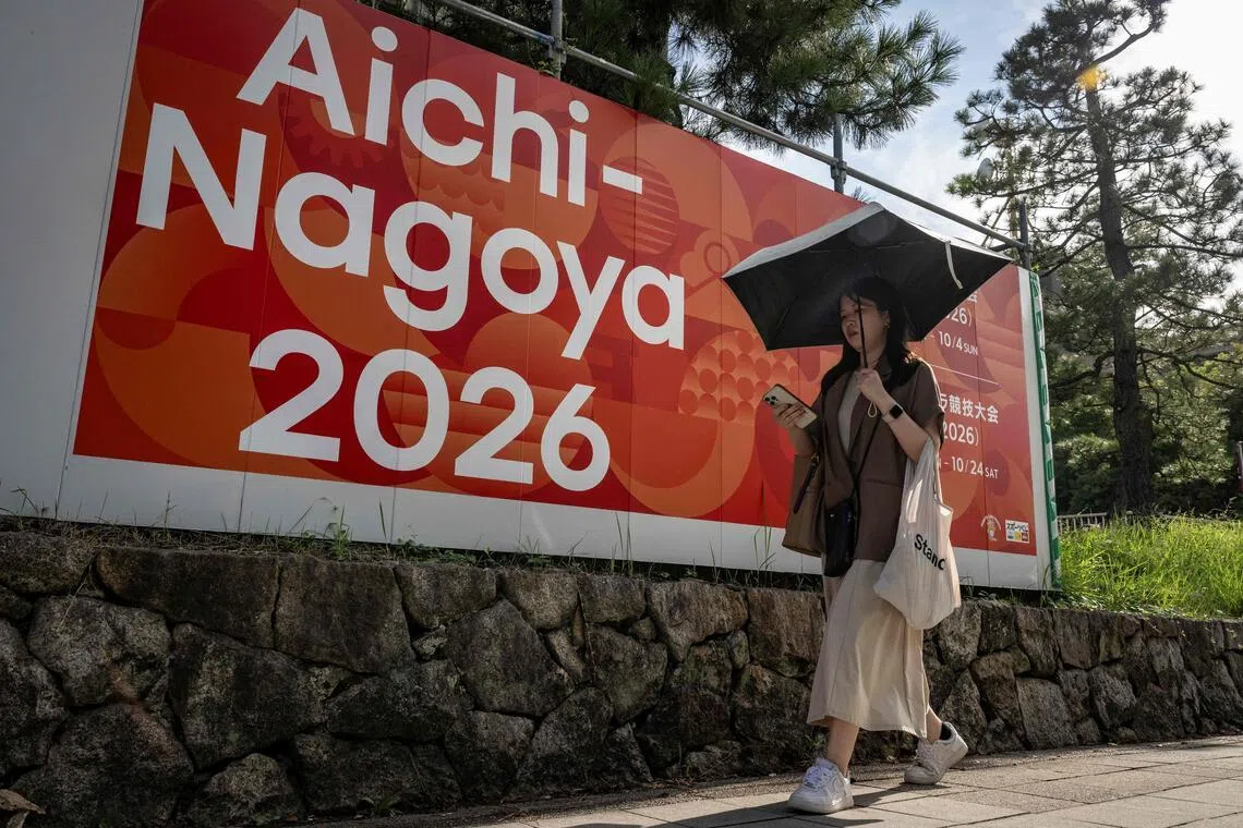 This picture taken on September 8, 2025, shows a woman walking past an advertisement for the 2026 Aichi-Nagoya Asian Games in Nagoya, Aichi prefecture. The Games will take place from Sept 19 to Oct 4, 2026.