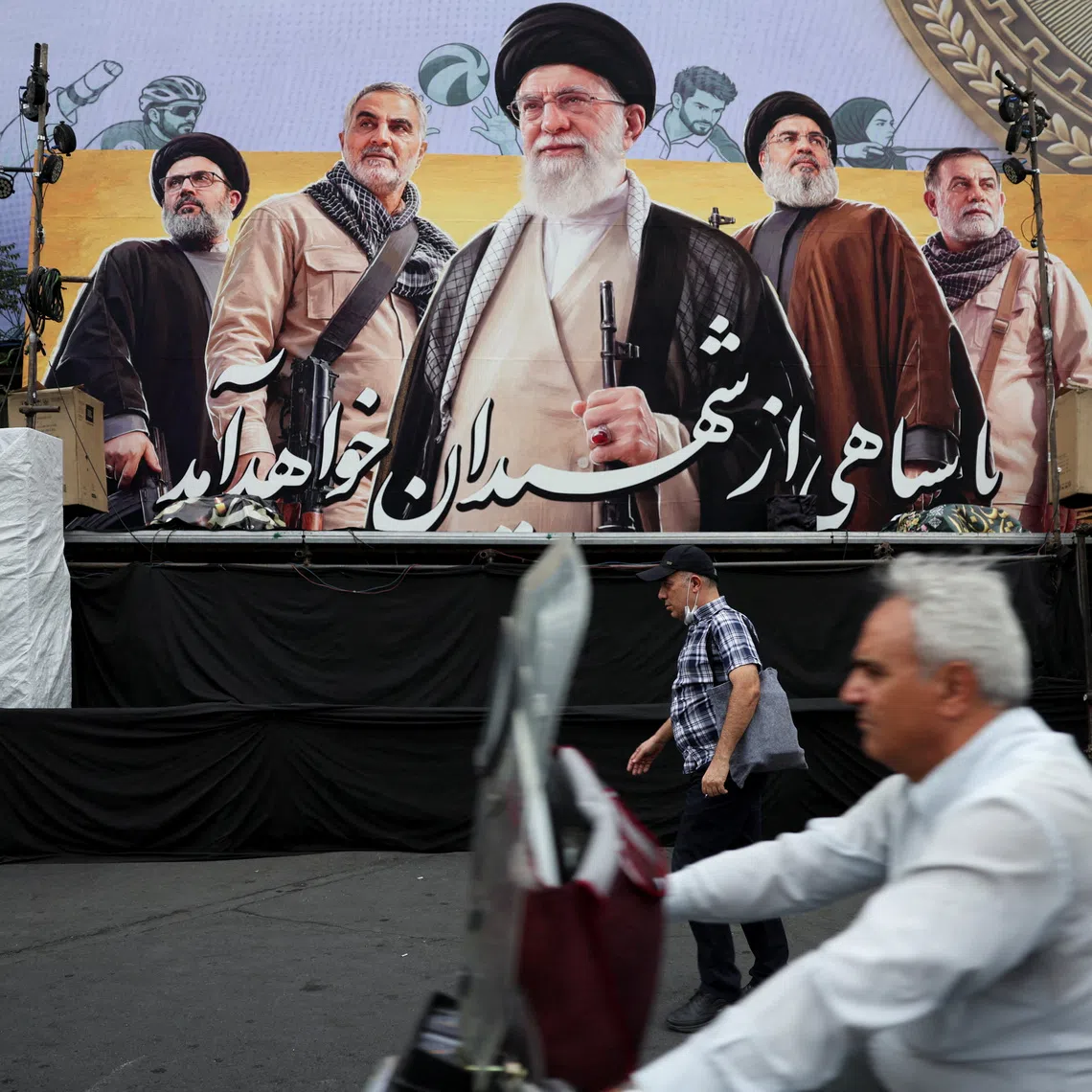 FILE PHOTO: A man walks past a bilbord depicting Iran's late Supreme Leader Ayatollah Ali Khamenei, the late former Hezbollah leader Hassan Nasrallah and the late military commander Qassem Soleimani, on a street in Tehran, Iran, October 6, 2026. Majid Asgaripour/WANA (West Asia News Agency) via REUTERS