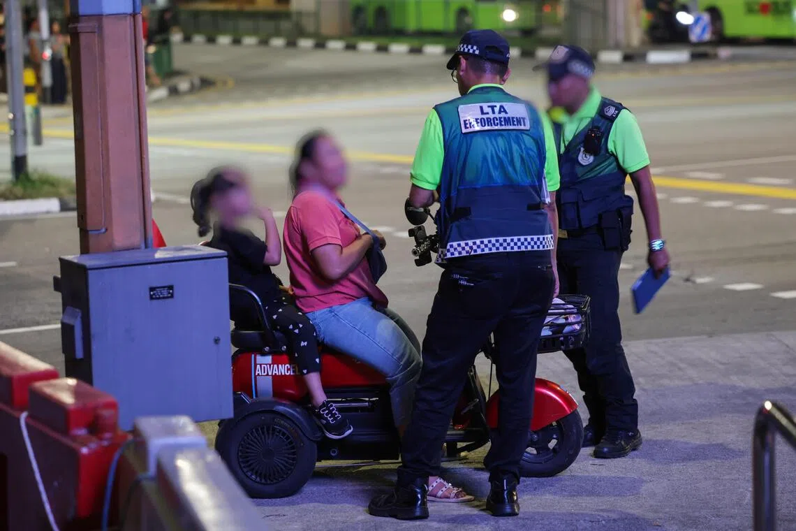 LTA enforcement officers speaking to a PMD user during the enforcement checks in Northpoint City in Yishun on Aug 3.
