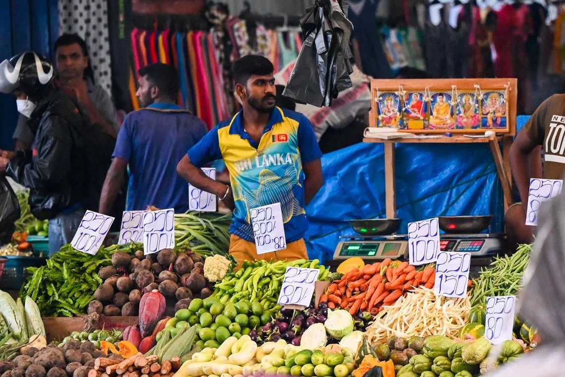 A vendor waits for customers at a vegetable market in Colombo on October 12, 2022. (Photo by ISHARA S. KODIKARA / AFP)