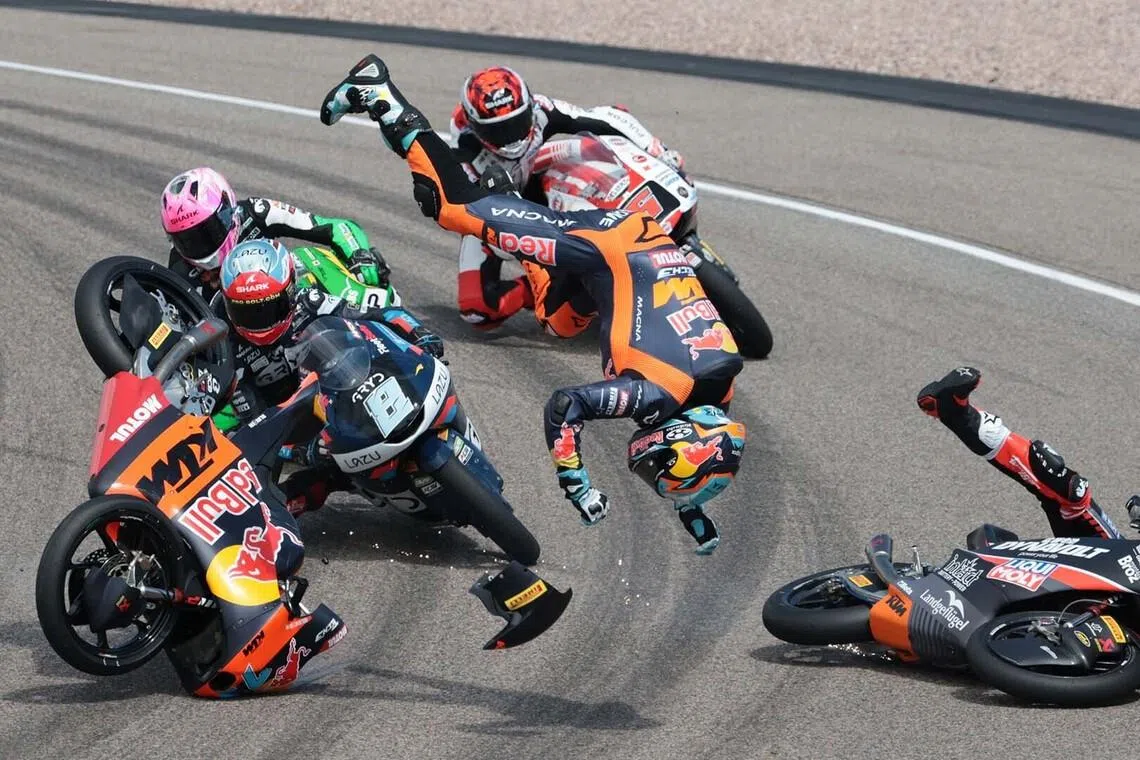 TOPSHOT - ALTERNATIVE CROP - Red Bull KTM Tech3 Team's Argentinian driver Valentin Perrone (C, flying head over heels through the air) and Spanish driver Marcos Uriarte (R, falling on the racetrack) crash during the Moto3 race at the Sachsenring race track in Hohenstein-Ernstthal near Chemnitz, eastern Germany, on July 12, 2026, ahead of the German Motorcycle MotoGP Grand Prix. (Photo by Ronny HARTMANN / AFP) / ALTERNATE CROP