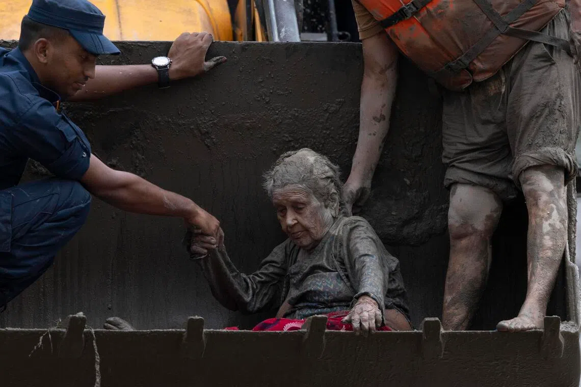 Rescuers transport an elderly woman rescued from a Devighat old age home following a flash flood in Trishuli Bazar, Nuwakot district, Nepal on Aug 26.
