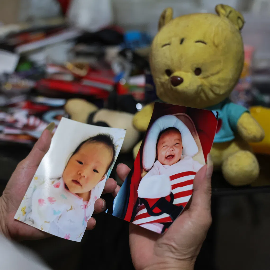 Megan Khung's grandmother, Madam Chua, looking at Megan's baby photos. Madam Chua still keeps her granddaughter's pictures and toys in her one-room rental flat.