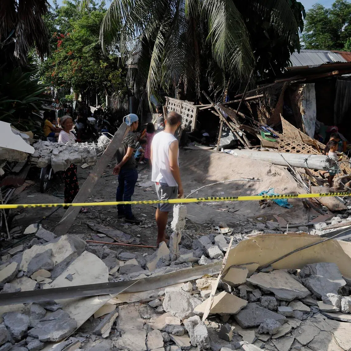 People inspect the damage at the site of a collapsed wall separating a warehouse-type facility and several homes, a day after an earthquake, in General Santos City, southern Philippines, on June 9.