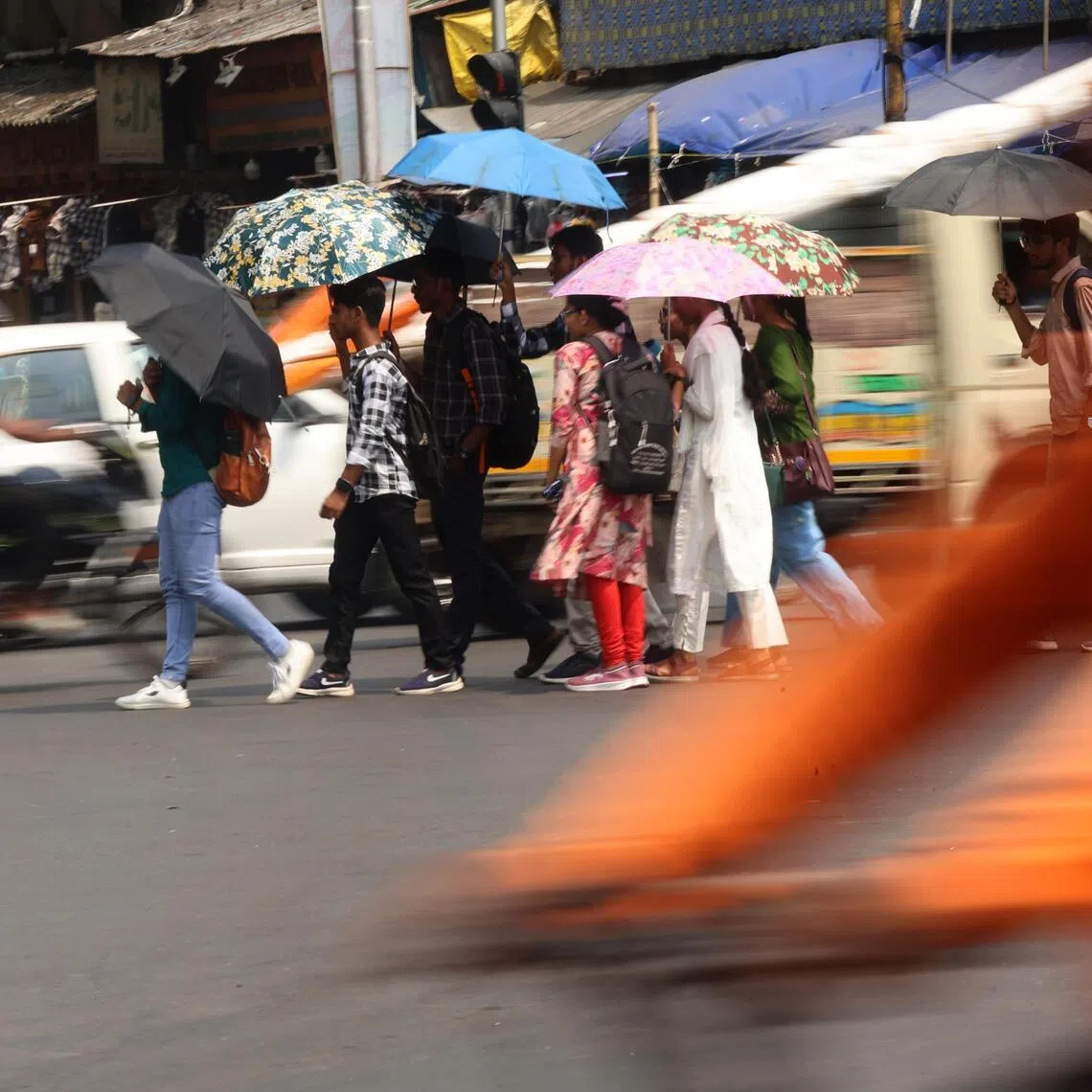 Indian commuters use umbrellas to protect themselves from the sun during a hot afternoon in Kolkata, India, on May 26, 2026. 