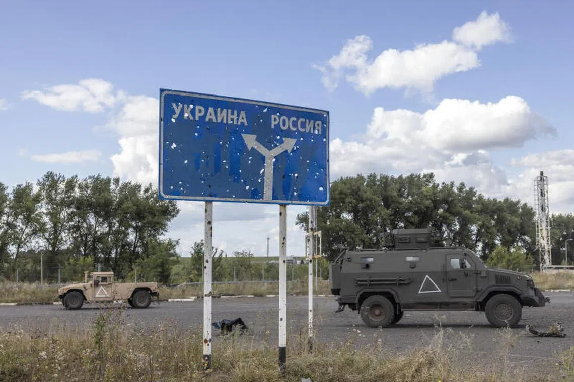 FILE — Ukrainian military vehicles pass a sign reading Ukraine, left, and Russia near the destroyed Russian border post on the Russian side of the Sudzha border crossing with Ukraine on Aug. 12, 2024. The publication of a 31-page detailed analysis was a sign that a ceasefire has gone from a theoretical exercise to an urgent and practical issue. (David Guttenfelder/The New York Times)