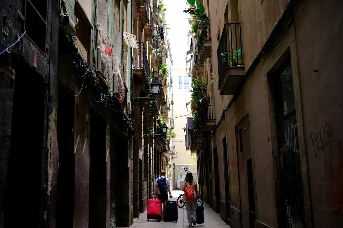 FILE PHOTO: Tourists walk with their suitcases in Gothic Quarter, in Barcelona, Spain June 24, 2024. REUTERS/Nacho Doce/ File Photo