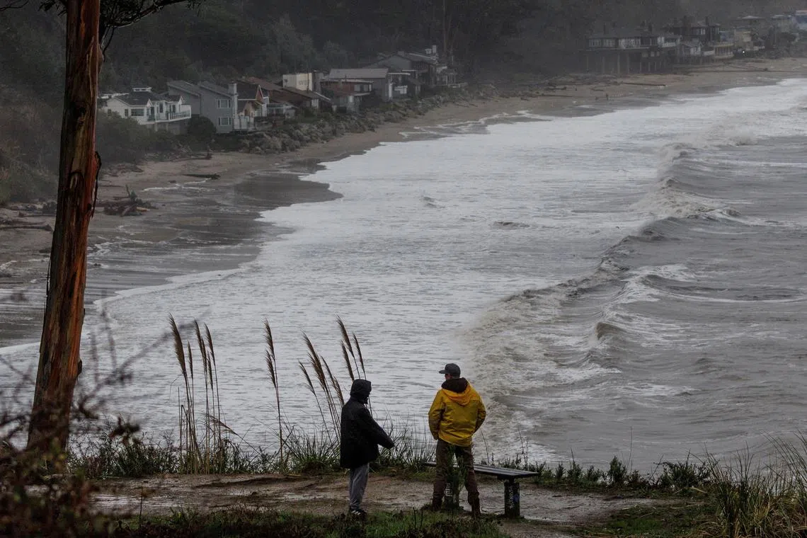 Local residents walk along the coastal line near Santa Cruz as rainstorms approach northern California.