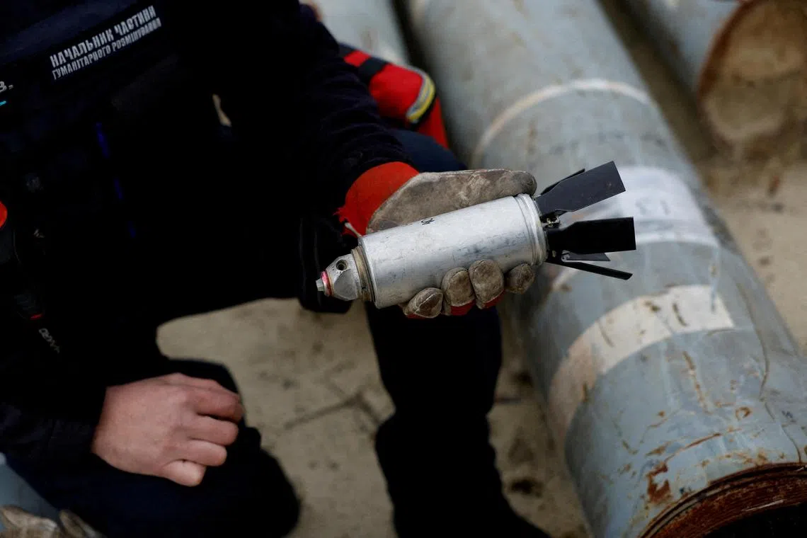 A Ukrainian soldier holds a defused cluster bomb used by the Russian army.