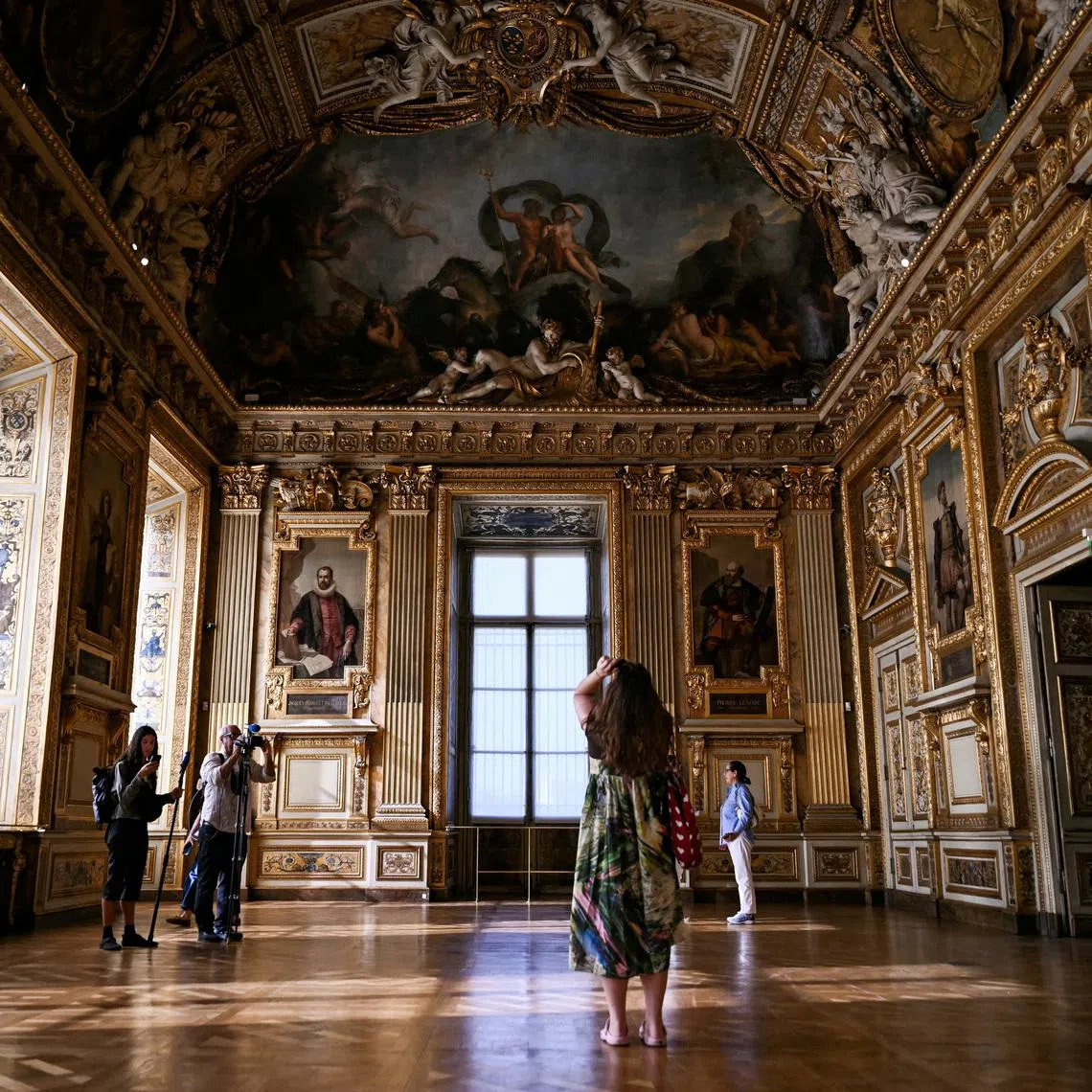 Visitors stand near the window at the Louvre Museum’s Apollo Gallery that two burglars smashed during a daring heist nine months ago.