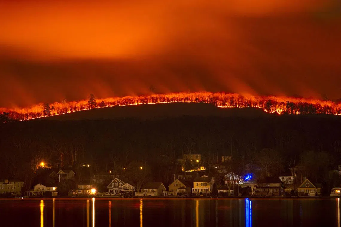 An unusual wildfire spreads across Greenwood Lake in New York, burning homes.