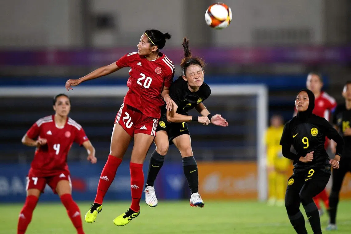 Quinley Quezada (in red) of Philippines fighting for the ball with Malaysia's Jaciah Jumlis in their SEA Games women's football group match at the Army Stadium in Phnom Penh.