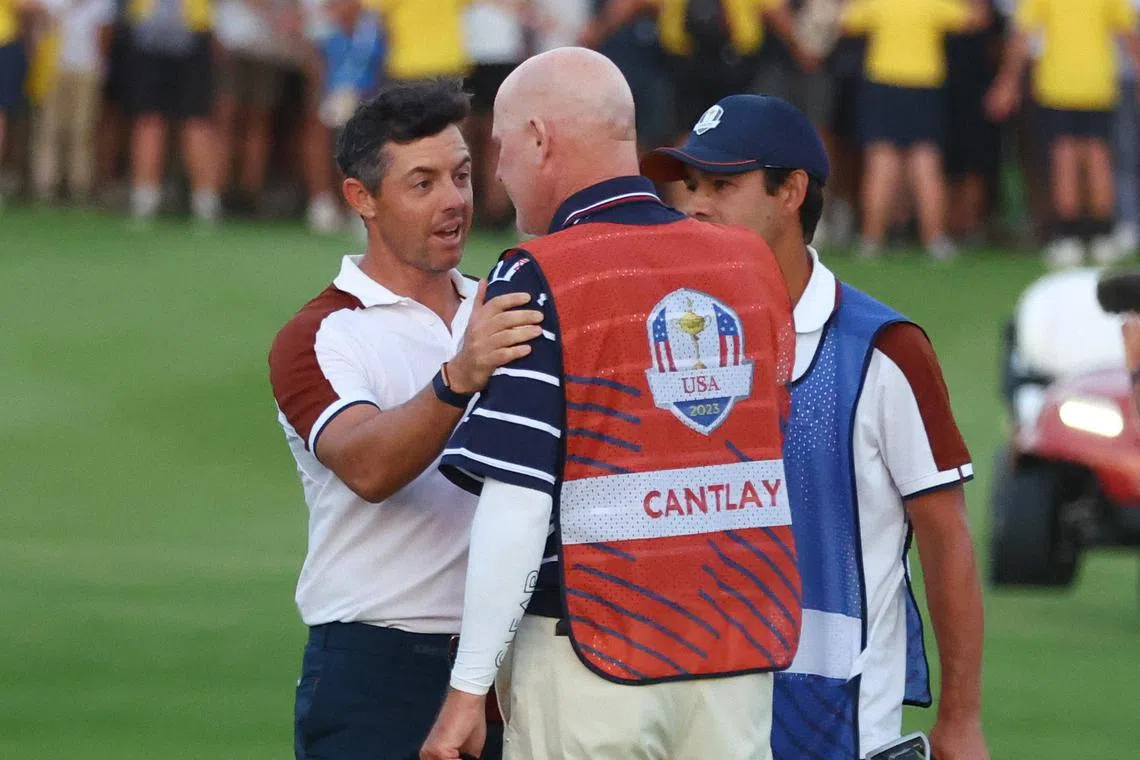 Team Europe's Rory McIlroy speaks with Joe LaCava, the caddie for Team USA's Patrick Cantlay, on the 18th green after their fourball match.