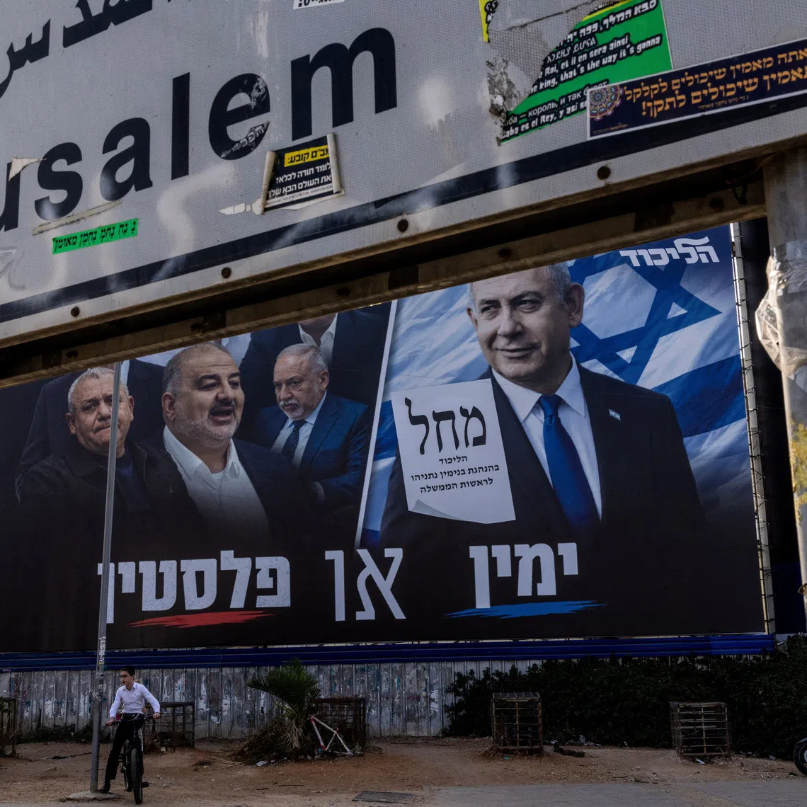 A boy sits on his bicycle next to a campaign banner of Netanyahu’s Likud party on Oct 25, ahead of the Israeli parliamentary election, in Bnei Brak, Israel.