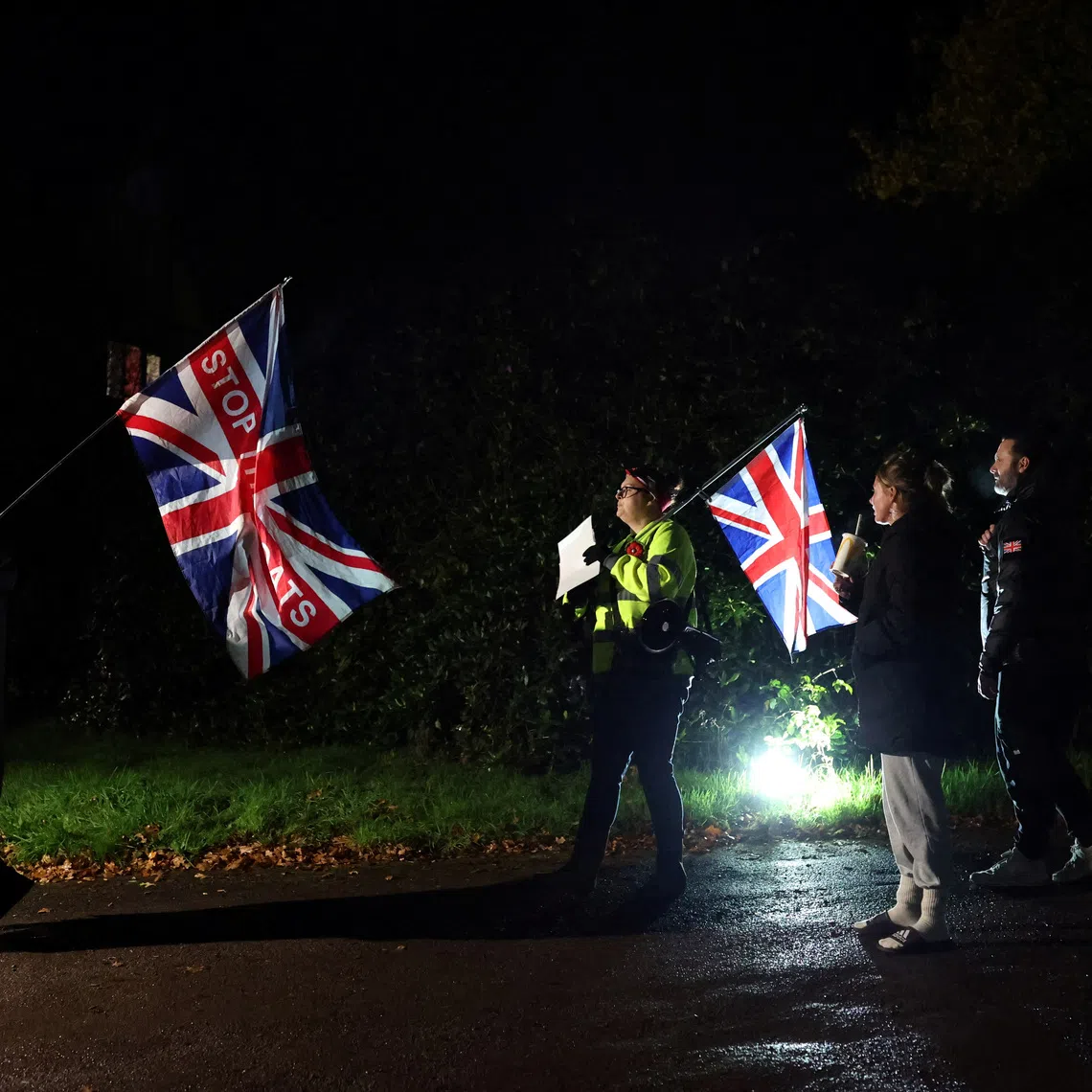 Protesters hold Union Jack flags outside the Cisswood House Hotel, believed to house asylum seekers during an anti-immigration protest in the village of Lower Beeding, near Horsham, Britain November 18, 2025. REUTERS/Hannah McKay