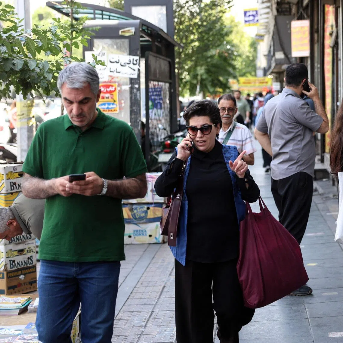 Iranians walk through a street in Tehran on June 18. The United States and Iran have signed a deal to end the Middle East war, with a ceremony set for June 19 in Switzerland that will mark the start of a 60-day negotiation period.