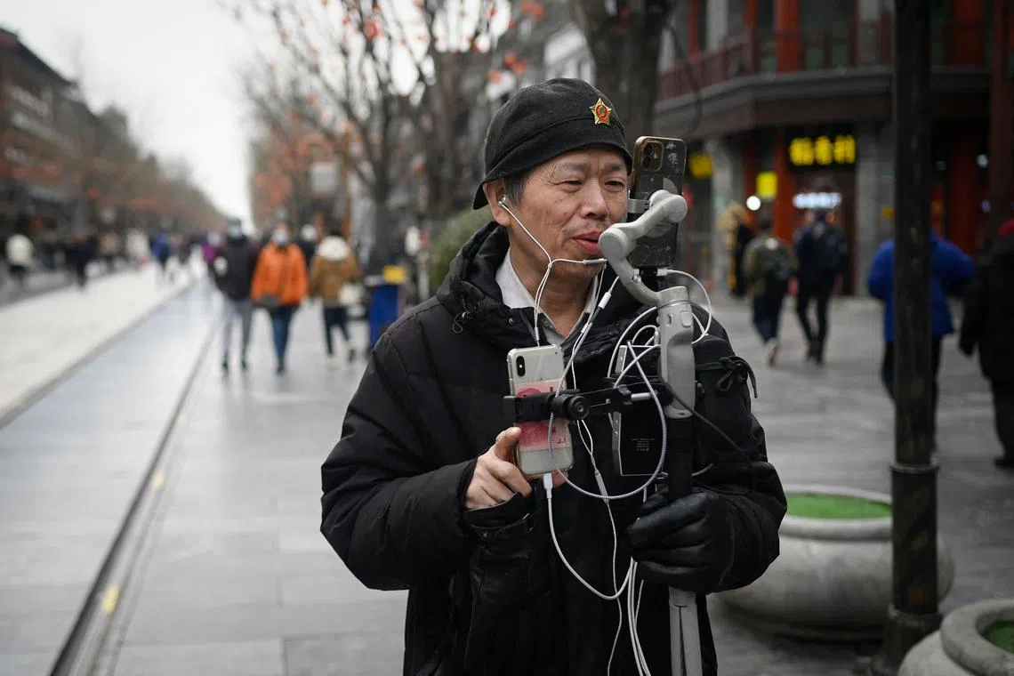 A man uses his mobile phone to live-stream on a shopping street in Beijing on February 28.