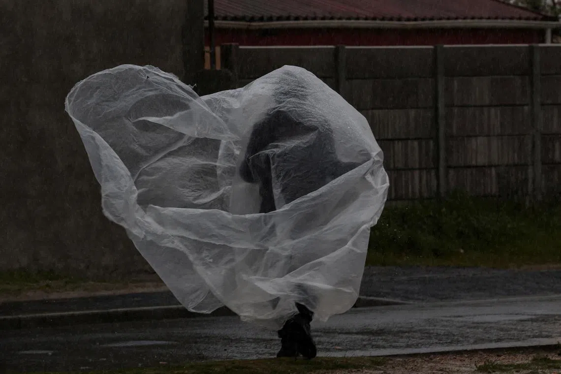 A man covering himself with a sheet of plastic on the Cape Flats during heavy rain in Cape Town, South Africa, Sept 14.