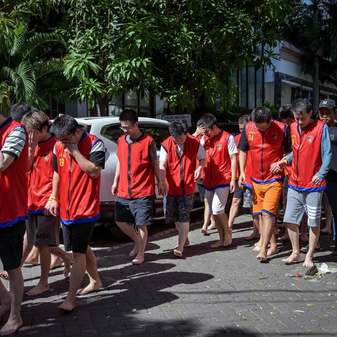 Indonesian police escorting a group of foreign suspects before authorities hold a press conference on an online fraud case in Surabaya, Indonesia, on May 8.