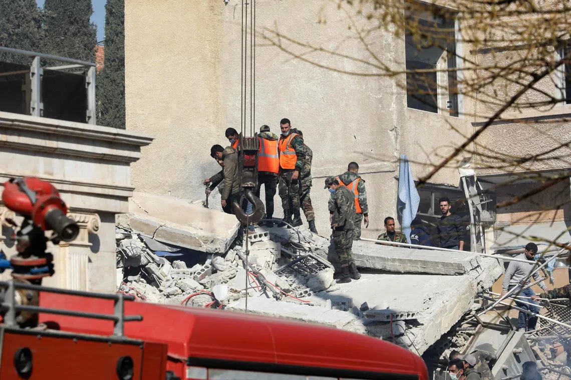 Security and emergency personnel search the rubble of a building destroyed in a reported Israeli strike in Damascus.