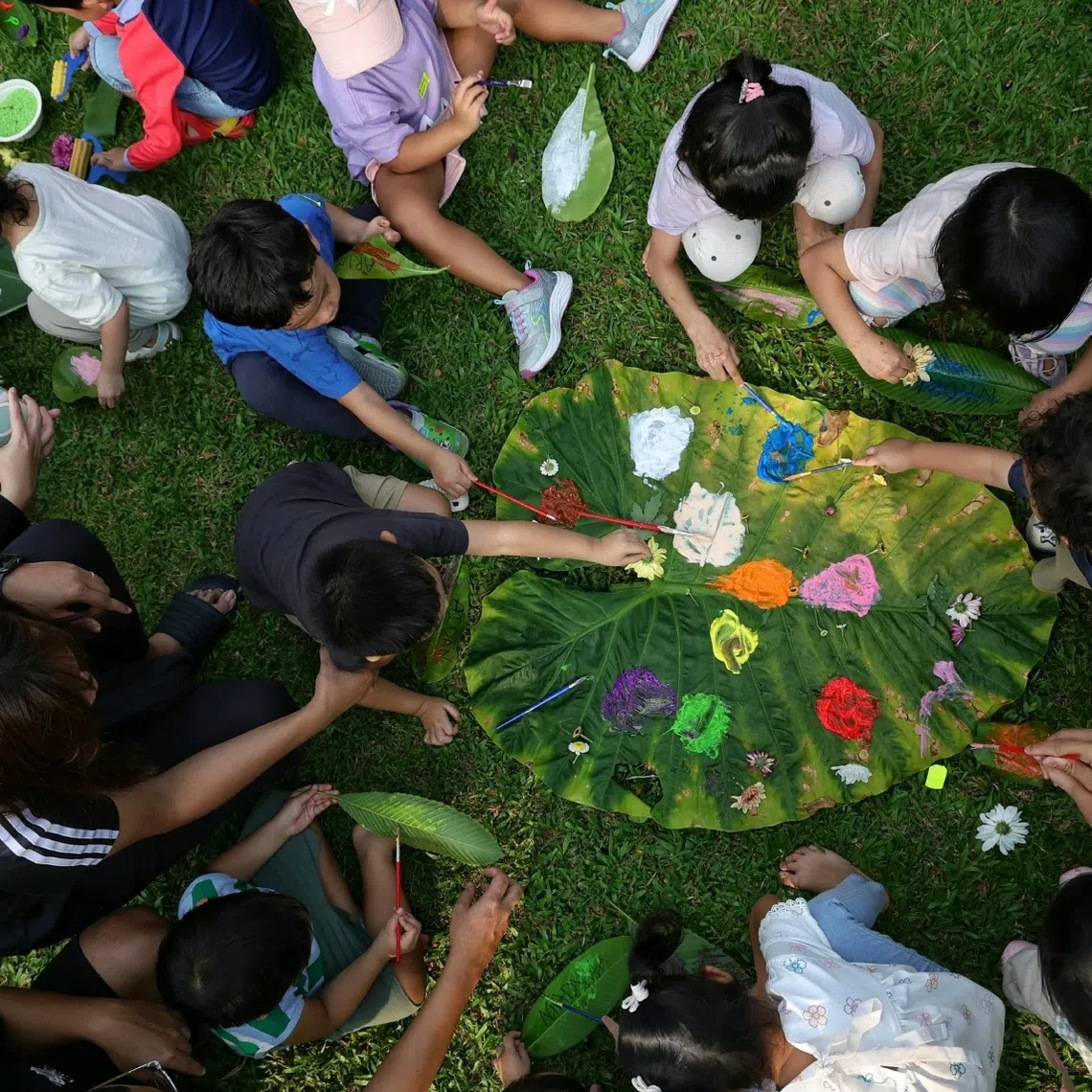 Children paint on leaves and decorate them before hanging their works of art out to dry during an outdoor playdate organised by Madam Nurul Aqilah Zakaria.