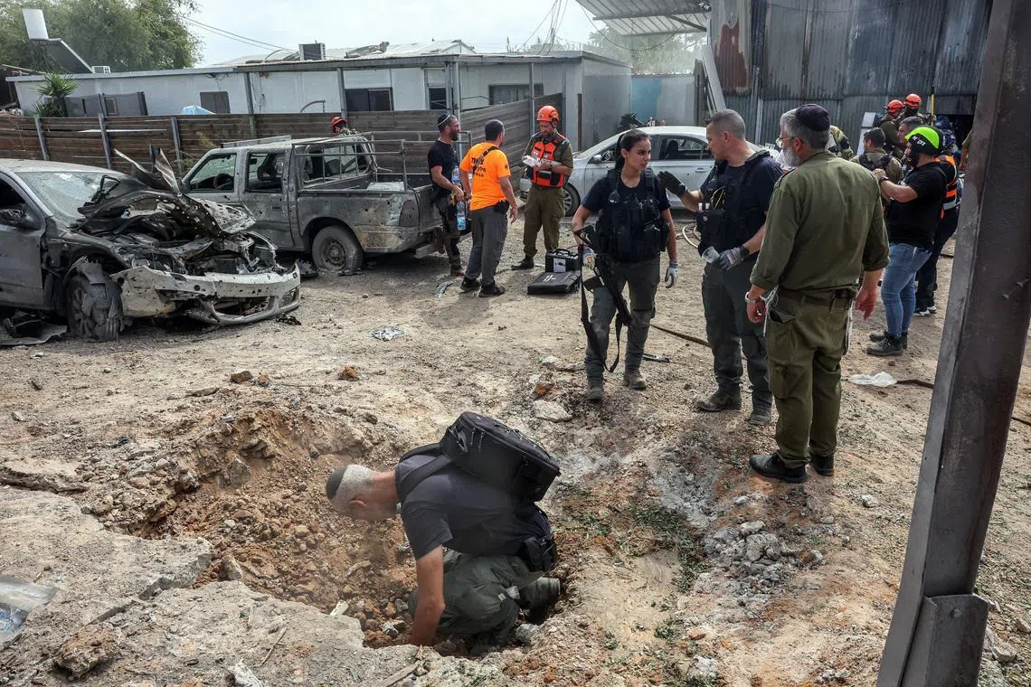 A security official investigates the crater formed when a projectile landed, after Hamas' armed wing said it attacked Tel Aviv with a missile salvo, amid the ongoing Israel-Hamas conflict, in Kfar Chabad, Israel, October 7, 2024. REUTERS/Itai Ron/File Photo
