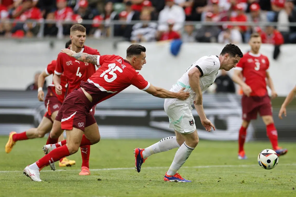 epa11398471 Austria's Michael Gregoritsch (R) and Switzerland's Cedric Zesiger in action during the international friendly soccer match between Switzerland and Austria, in St. Gallen, Switzerland, 08 June 2024.  EPA-EFE/PETER KLAUNZER