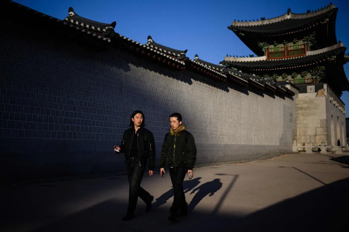 Two men walk alongside the walls of Gyeongbokgung Palace in Seoul.