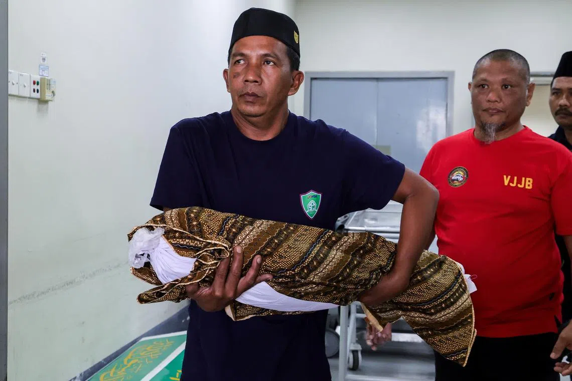 The body of the suspected abuse victim being carried by his grand-uncle Ruslan Ahmad for burial.