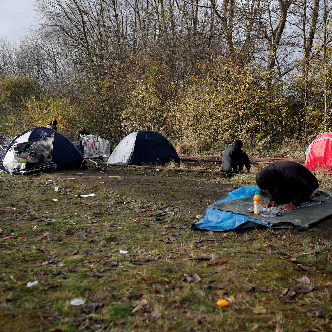 FILE PHOTO: A migrant prays at a makeshift migrant camp in Loon Beach, the day after 27 migrants died when their dinghy deflated as they attempted to cross the English Channel, in Dunkerque near Calais, France, November 25, 2021. REUTERS/Johanna Geron/File Photo