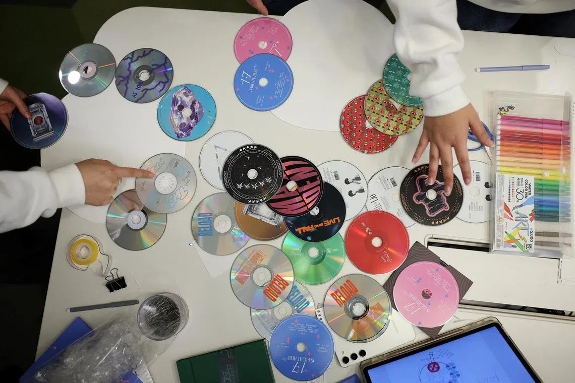 Kpop4planet activists work on signs made of CDs ahead of talks in Seoul over a treaty to control plastic waste.