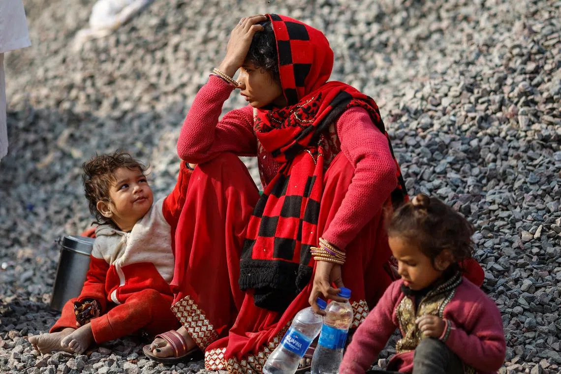 A relative of a stampede victim sits between children outside a hospital mortuary following a stampede that occurred before the second \"Shahi Snan\" (royal bath), at the \"Maha Kumbh Mela\" or the Great Pitcher Festival, in Prayagraj, India January 29, 2025. REUTERS/Adnan Abidi