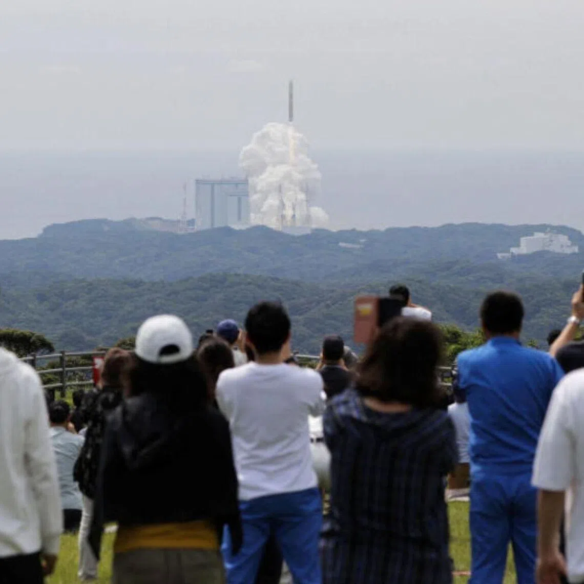 People watch Japan's H3 rocket as it lifts off from the Tanegashima Space Center in south-western Japan, on June 12.