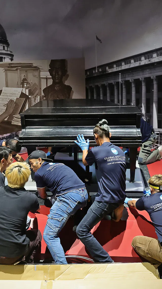 (SUGGESTED MAIN PIC 2) A 10-men team of art handlers and members of the exhibition team shifting the late composer Zubir Said's piano, guided by its curator and conservator, into position in the Towards a New Identity section of the gallery on July 21, 2026.