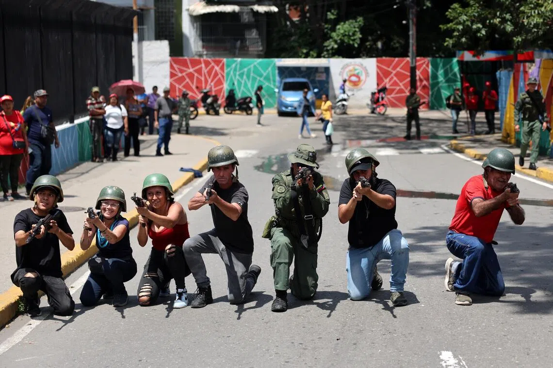 People in Caracas, Venuezela, aim weapons during military training conducted by the Bolivarian National Armed Force on Sept 20.