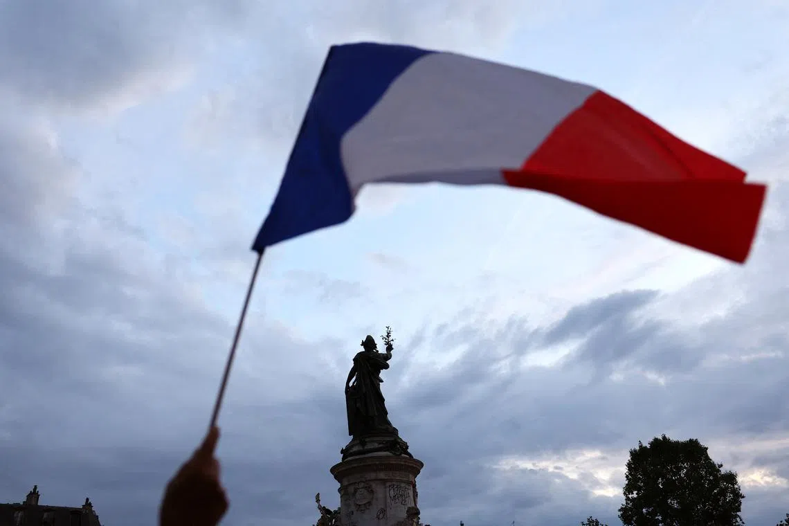 A protesters holds a French national flag as people gather to protest against the French far-right Rassemblement National (National Rally - RN) party, at the Place de la Republique following partial results in the first round of the early 2024 legislative elections, in Paris, France, June 30, 2024. REUTERS/Fabrizio Bensch