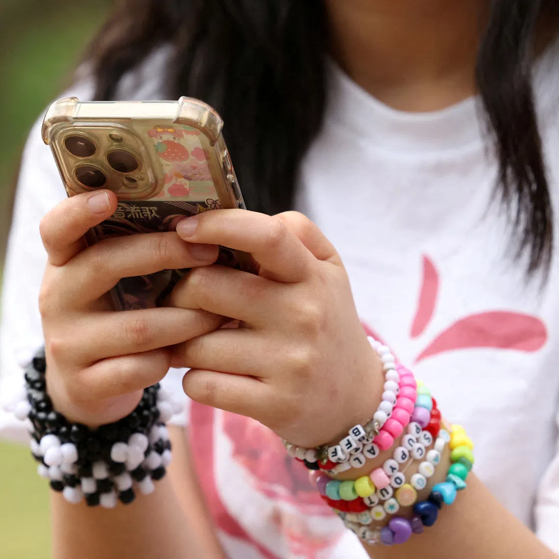 FILE PHOTO: A girl poses holding her phone after an interview discussing Australia's social media ban for users under 16, which is scheduled to take effect on December 10, in Sydney, Australia, November 22, 2025. REUTERS/Hollie Adams/File Photo