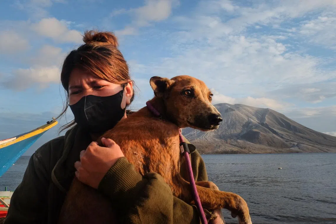 A volunteer carries a dog as they bring back animals from the abandoned area at the foot of Mount Ruang volcano in Sitaro, North Sulawesi, on May 4.