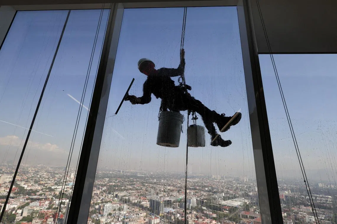 A worker cleaning windows on the exterior of an office building in Mexico City, on March 23.
