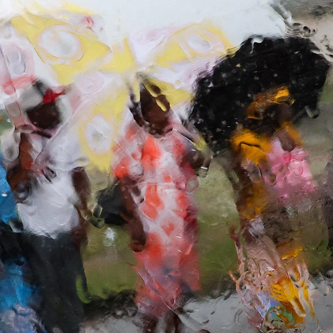 People using umbrellas to shelter from the rain as they wait on a street for Pope Leo XIV to pass by, on the day of the pope's visit to the Bata prison, in Bata, Equatorial Guinea, April 22.