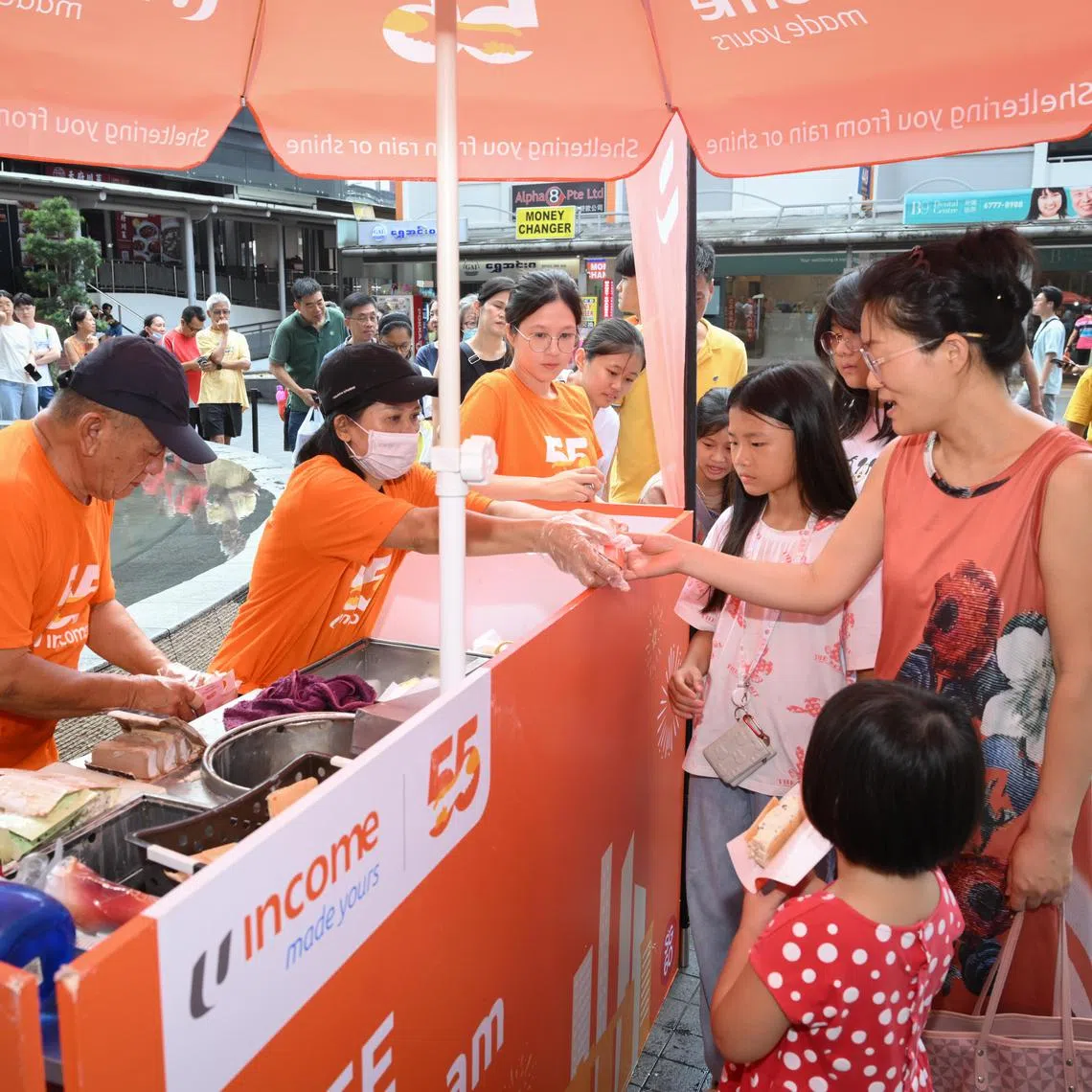 Ice cream vendor Cheong Peng Siong and his assistant Tang Chun Tan serving customer Ren Hui Li and her children near Clementi Mall on Aug 10.