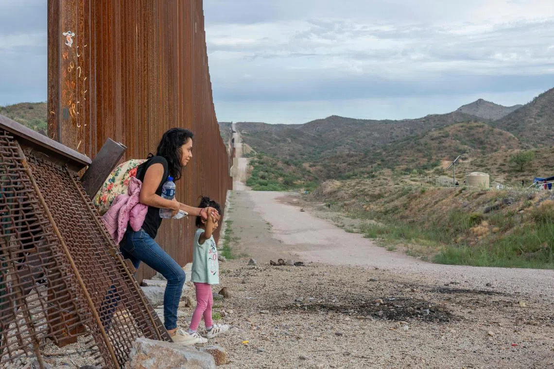 A migrant family crosses through border fencing into the US on June 26, 2024 in Ruby, Arizona.