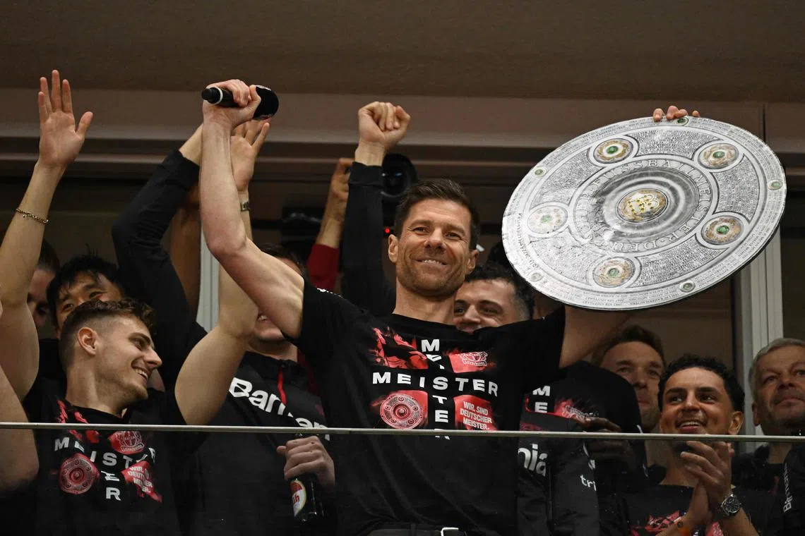 Bayer Leverkusen coach Xabi Alonso celebrates with a mock-up of the Bundesliga trophy with his players after the 5-0 win over Werder Bremen.