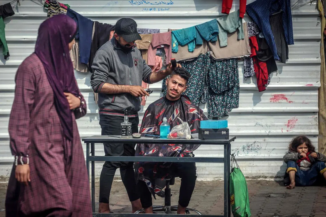A man gets a hair cut in a school turned into shelter for displaced in Rafah in the southern Gaza Strip, on February 19, 2024, amid the ongoing conflict between Israel and the militant group Hamas. Nearly 1.5 million displaced Palestinians are trapped in Rafah -- more than half of Gaza's populations -- seeking shelter in a sprawling makeshift encampment near the Egyptian border. (Photo by MOHAMMED ABED / AFP)