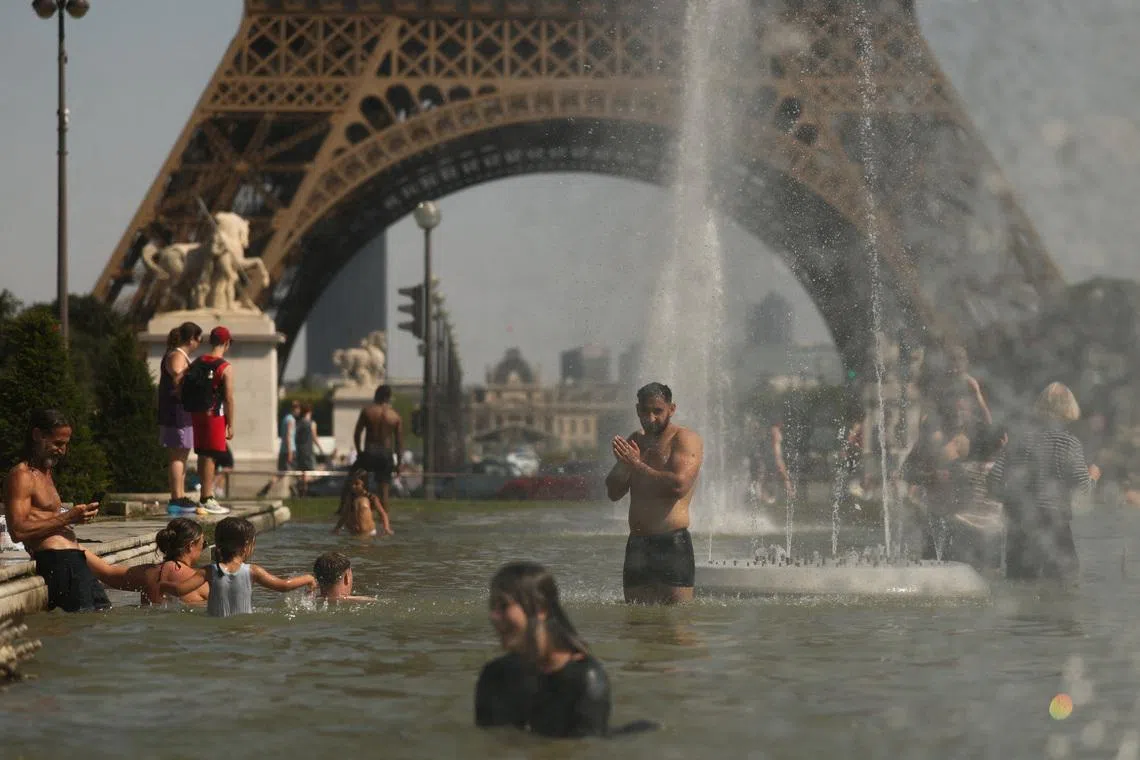 People cool off at the Trocadero Fountain near the Eiffel Tower as temperatures rise during a heatwave affecting a large part of France.